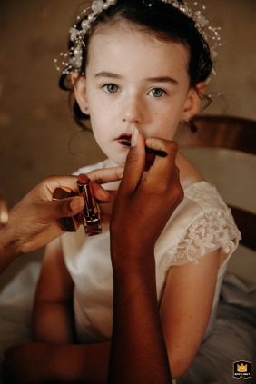 In Lot-et-Garonne - At the couple's home, their daughter looks at the camera while having lipstick applied during preparations.